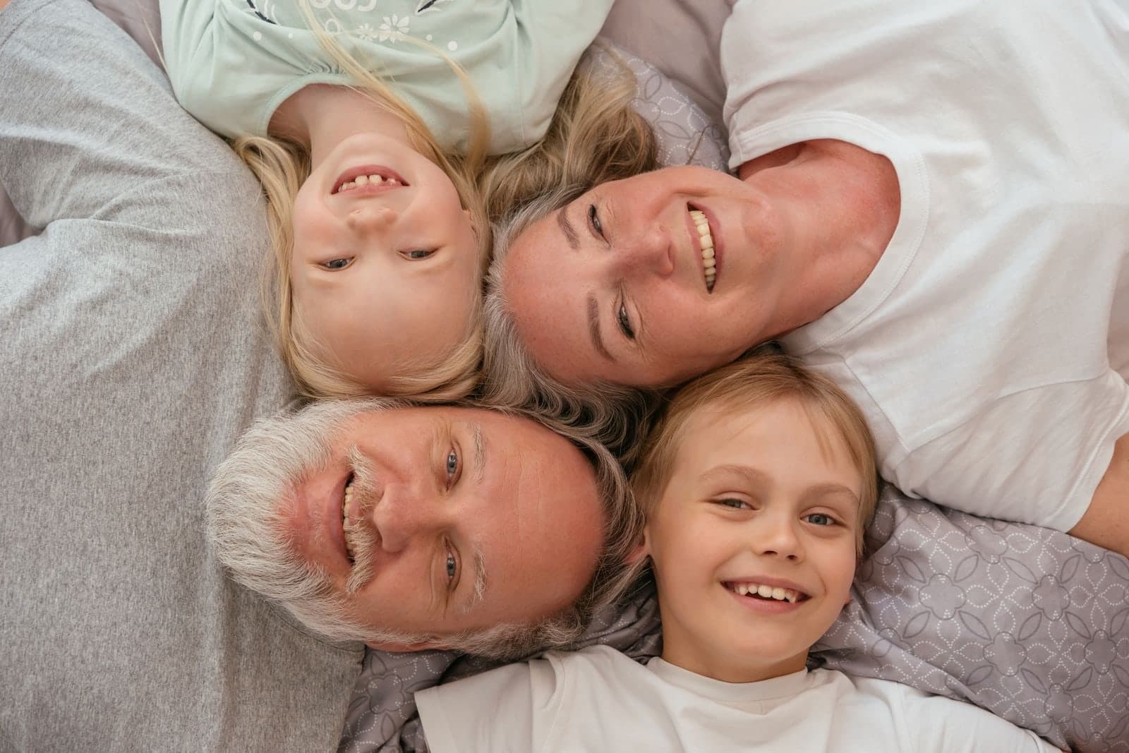 Grandparents and grandchildren lying together, heads touching, all smiling