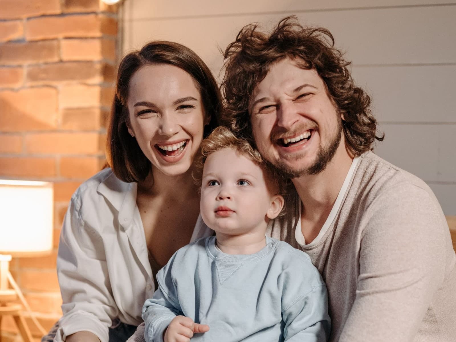 A mother, father and their young son laughing together at home