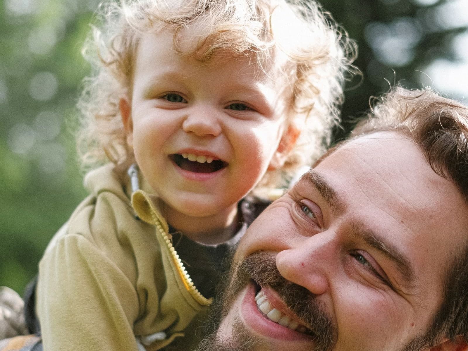 A father and his young son laughing together outdoors